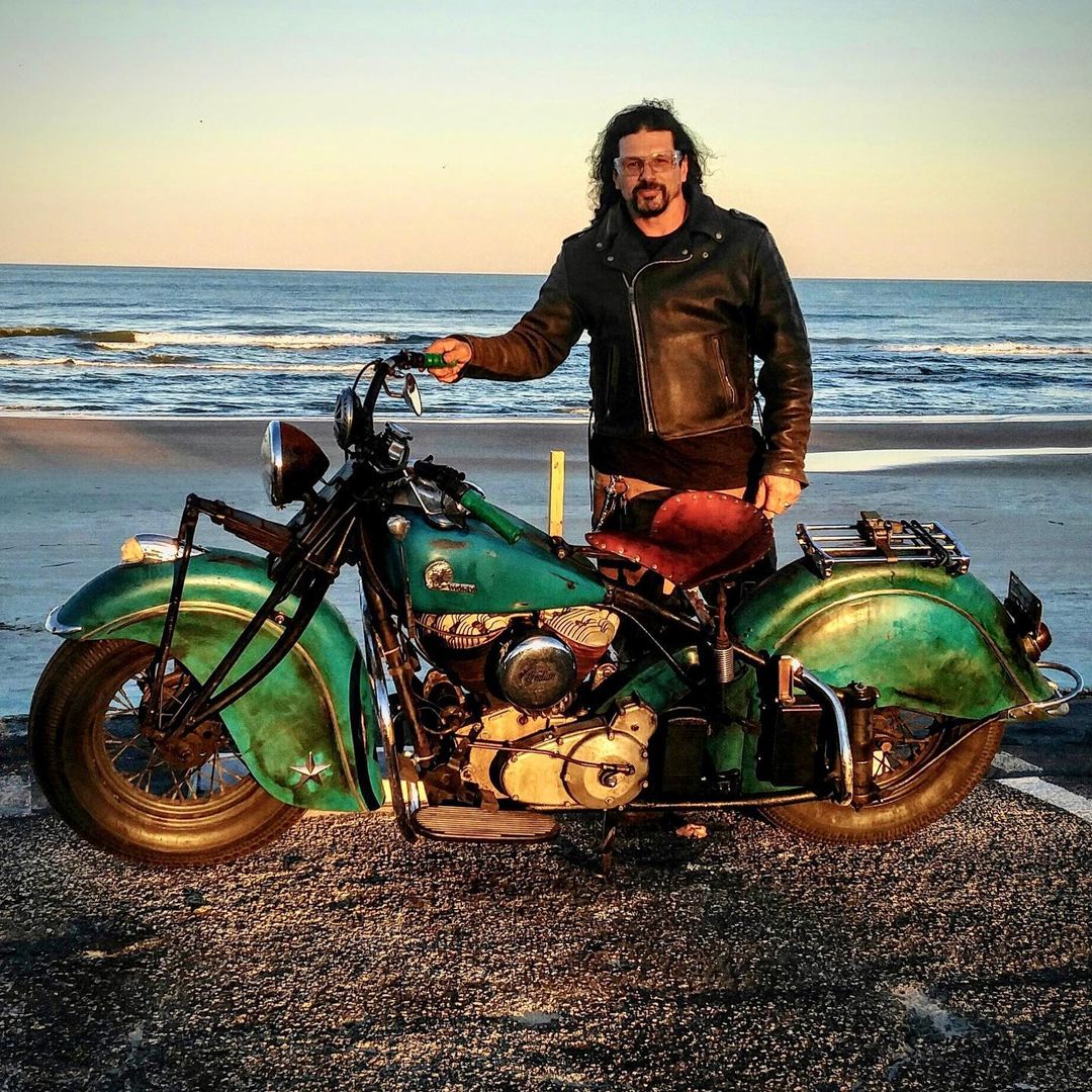 Billy Lane posing with bike at the beach